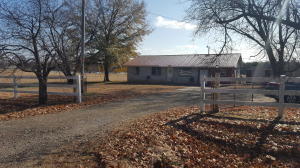 JUST THE RIGHT SIZE for your family. Three bedroom, 1.5 bath with a big 1 acre fenced yard and plenty of room to run. It has large trees, outbuilding and location out of town but close to town. The home is brick exterior with a metal roof. Many updates are ongoing inside including fresh paint, new flooring and more! Spacious laundry room and a nice attached work shop with electricity. Ready for a new owner!