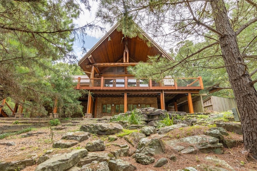 Tucked away just off Crossover, this is no ordinary Fayetteville home—it’s a true lodge retreat. Built by Pioneer Log Homes of British Columbia, massive timbers were shipped from Canada and pieced together here, creating a one-of-a-kind “treehouse” feel. Just over 4,000 Sq Ft with an easy-flow layout featuring open living spaces, main-level master, a guest room, lofted views, and plenty of room to spread out.
Everywhere you look, details tell a story; antler hardware, hand-painted murals, rustic sinks, and wood finishes that make the home feel like a mountain escape in Northwest Arkansas. Step outside to a creek running beneath the house, a duck pond, and decks tucked into the trees. Peaceful, private, and minutes from town, this property feels like a getaway every time you arrive.