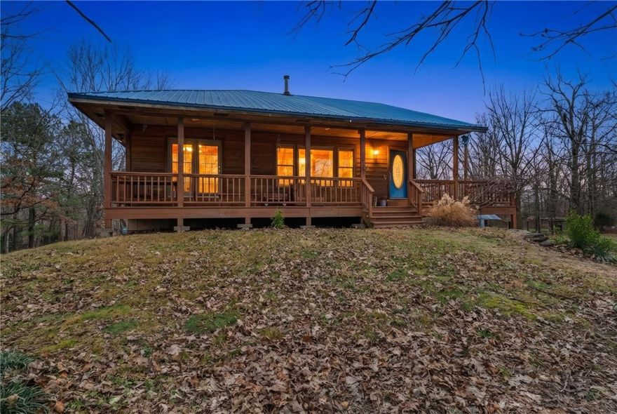 Country living without sacrificing accessibility! This property is just 15 minutes from Walmart Headquarters and Downtown Bentonville, making it a rare opportunity to live sustainably while staying connected. With the perfect blend of privacy, quality craftsmanship & convenience, this exceptional 10-acre property is mostly flat and highly usable—ideal for homesteading. The 2,500sqft cedar cabin offers timeless character and thoughtful construction, 2 bedrooms & 2.5 baths with three-quarter-inch hardwood flooring throughout. Solid oak cabinets anchor the spacious kitchen, while double-paned windows and a whole-home water softener add comfort and efficiency. The home is well insulated with Thinsulate 6" on exterior walls and 4" on interior paired with a metal roof. A large 3-car garage with insulated doors is supported by steel beams, as is the porch, for long-term durability. Additional features include frost-proof drains, a laundry chute, & seasonal wisteria trees that grace the porch with color and charm.