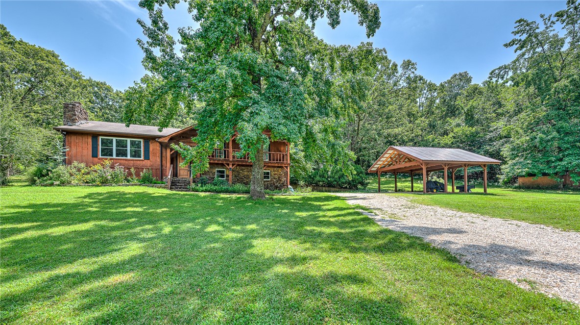 Enjoy the best of both worlds—peaceful country living with in-town convenience! This native stone & wood-sided split-level home sits on scenic, fenced property with hardwood trees and open space. A barn with electricity and water—previously used for horses—offers great potential for hobbies, animals, or storage. Inside, the split-level layout adds flexibility, with a spacious lower level ideal for an apartment, guest suite, or home office. The main level living room features a fireplace with an Ashley wood stove insert for a warm, inviting focal point. The large kitchen includes an eat-in dining area, ample cabinetry, pantry, and generous counter space. Double-pane, double-hung windows throughout enhance comfort and efficiency. Enjoy multiple decks—perfect for outdoor dining or relaxing in the natural setting. Additional highlights include a newly built, wood-beam 2-car carport and a multi-flo septic system. Centrally located with easy I-49 access—just 6.5 miles from the University of Arkansas.