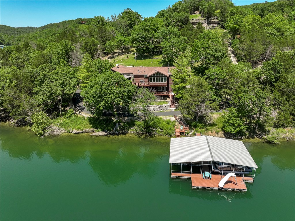 Quintessential Lakefront Experience with direct access & open views of pristine Beaver Lake. 2 coveted slips in a 4 slip dock w/swim deck & slide. Expansive decks & covered pergola offer breathtaking year around views of the lake & surrounding paradise. Covered front porch welcomes you home to this charming 3/4 bedroom, 3 full bath dream home featuring 2 levels of living space making it the ideal luxury residence/family retreat. Main floor family room boasts a rustic stone fireplace, awesome sun room with cathedral ceiling, cozy den, & breezeway. Culinary enthusiasts love the stunning kitchen featuring a copper sink, center island, breakfast room, & window overlooking upper deck & lake. Expansive upper & lower decks offer breathtaking views of this slice of paradise. Remodeled primary with en-suite offering whirlpool tub, seperate shower, & walk-in closet. Walkout lower level offers huge 3rd brm, full bath, 2nd family room/game area & amazing wet bar. Oversized garage offers lots of room for your toys. Exceptional