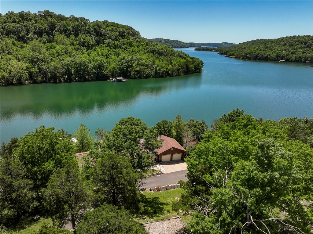 Quintessential Lakefront Experience with direct access & open views of pristine Beaver Lake. 2 coveted slips in a 4 slip dock w/swim deck & slide. Expansive decks & covered pergola offer breathtaking year around views of the lake & surrounding paradise. Covered front porch welcomes you home to this charming 3/4 bedroom, 3 full bath dream home featuring 2 levels of living space making it the ideal luxury residence/family retreat. Main floor family room boasts a rustic stone fireplace, awesome sun room with cathedral ceiling, cozy den, & breezeway. Culinary enthusiasts love the stunning kitchen featuring a copper sink, center island, breakfast room, & window overlooking upper deck & lake. Expansive upper & lower decks offer breathtaking views of this slice of paradise. Remodeled primary with en-suite offering whirlpool tub, seperate shower, & walk-in closet. Walkout lower level offers huge 3rd brm, full bath, 2nd family room/game area & amazing wet bar. Oversized garage offers lots of room for your toys. Exceptional