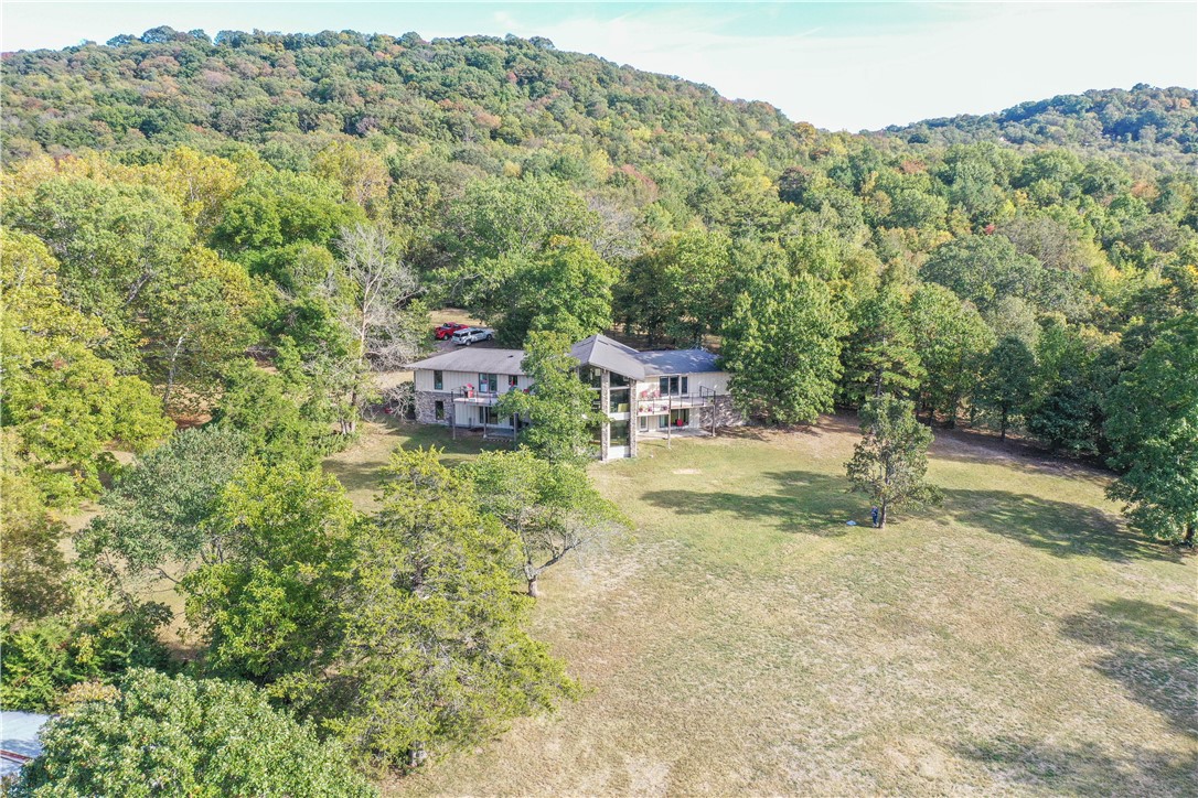 Beautiful Contemporary home with a lake view & park like setting. Walk in the front door and you will see the 4x8 Koi pond, custom built-ins, vaulted ceilings with floor to ceiling windows to take in the view. Kitchen boasts of SS back splash, ball bearing drawers, butcher block island, SS Kitchen Aide appliances including a 3 temperature beverage frig, double oven, 5 burner countertop range, microwave and refrigerator. Primary Suite has 2 walk in closets and access to a deck, primary bath has double vanities, soaking tub, large walk in shower with multiple shower heads, and a toto toilet. Home has 3 skylights, and 1 solar tube for even more natural light. Each room in the house was custom designed with high end finishes. Work shop in basement, separate breaker panel for a generator. Home has 400 AMP service. 1500 sq ft workshop. All this is on 5.8 acres.