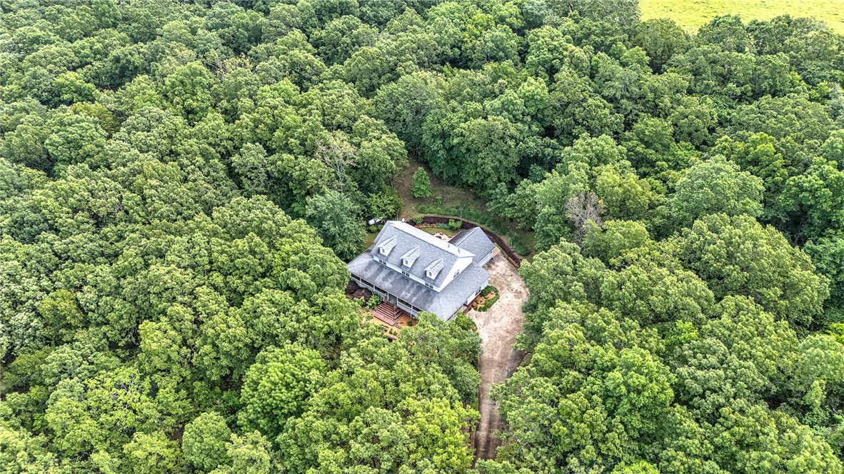 Discover this charming country farmhouse style home nestled on five wooded acres in the desirable Prairie Grove area. This spacious 3-bedroom, 3-bathroom home offers approximately 3,700 square feet of living space, complemented by a beautiful, recently remodeled kitchen (2021) featuring double ovens, a built-in freestanding ice maker, and a refrigerator that conveys.
The home boasts real wood flooring throughout and two primary bedrooms, ideal for flexibility and privacy. Enjoy the privacy and tranquility of your surroundings while relaxing on the expansive 1,500-square-foot covered wrap-around porch—perfect for outdoor entertaining.
Additional amenities include a heated and cooled 864-square-foot metal building (not included in the total square footage), perfect for a workshop or storage, and a long driveway lined with 25 exterior lamp posts that enhance the property's charm and security. The property offers the perfect combination of modern comforts and rustic appeal in a serene, wooded setting.