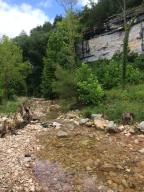 Beautiful bluff and hilltop views. Seasonal creek and runs underground year round. Only 2 miles off pavement with electricity on property. Beautiful homesites and lots of wildlife. County road frontage. New road to uphill homesites.