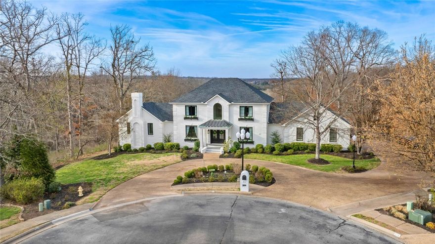 Tucked in the back of Hanover, this elegant home offers breathtaking views and an upscale designed interior. Natural light floods the 18' entry, highlighted by a statement chandelier and complemented by floor-to-ceiling wainscoting. The front rooms include an executive office and private theater. The rear of the home showcases a TRUE chef’s kitchen, family room, dining room with a discreet hidden door, sunroom, and walk-in pantry. Natural light from a wall of windows blurs the lines between indoors and out. Enjoy seasonal views across nearly 5 acres. The primary suite features a spa-like bathroom, expansive closet with built-in organization, and large bedroom with ceiling detail and fireplace. Upstairs offers 3 additional ensuite bedrooms and a flex room. The backyard oasis features a heated gunite infinity pool with tanning shelf and bubbler overlooking a park-like setting. Enjoy neighborhood bike trail access and proximity to all things Bentonville. Ask agent for detailed upgrade list including roof/HVAC/windows.