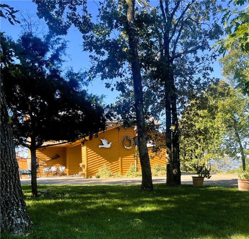 This 2336 sf home is set back with a circular drive. Mature trees pepper the well maintained yard in the front and pathways for a touch of whimsy in the back. Home has multiple rooms that can be used as extra bedrooms or living areas. Newer SS appliances in kitchen will convey at no cost. Kitchen has had countertops and flooring replaced in the past 5 years. Utility closet/pantry in kitchen has W/D to convey at no cost. Living room is flooded with natural light and houses a brick fireplace w/gas logs. Wood flooring is elegant and the small 1/2 bath makes this first floor an amazing space to entertain guests. Along the back of the house is an all-season room to enjoy the scenery any time of the year! Large master suite has double vanity and walk-in shower. Upstairs is a bonus living area w/ beamed ceiling and second master. Another all-season room along the back. Views will be the envy of all your guests as they revel in the mountains of the Ozarks. Solar panels are owned and electric bills just over $20 per month.