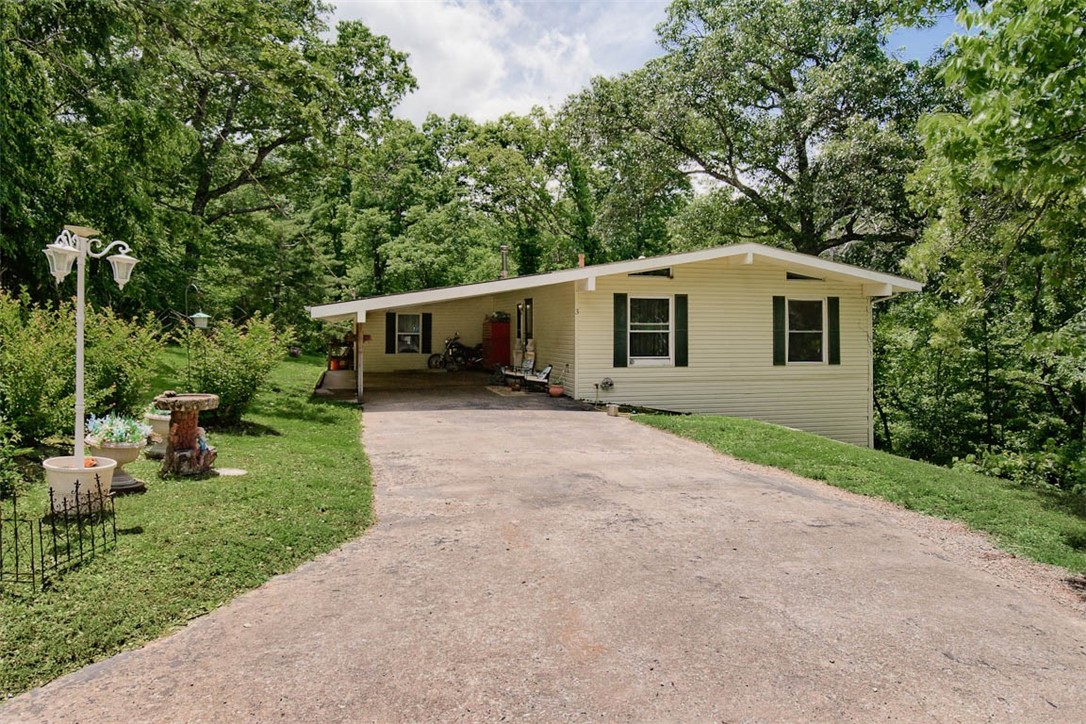 Welcome home to this charming two-bedroom, one-bath residence, complete with office and two lots, Ideally situated on a quiet cul-de-sac! Outdoor enthusiasts will appreciate the prime location to the Back 40 trail system that is just down the street & you are minutes from Lake Ann & Lake Brittany. Metfield Park is also close offering golf, swimming, playground, basketball, bike skills & tennis. You'll also enjoy quick access to downtown Bentonville & the new Walmart Campus, just a 22-minute drive. Step out from the dining room onto a covered deck, perfect for enjoying the private, serene wooded views of your 2 spacious lots totaling 0.69 acres & includes an 8x10 shed w/electricity. Recent updates: Roof was replaced in 2023, Trane 3-ton heat pump HVAC system in 2018. Septic system & vinyl windows were updated in the early 2000s. The laundry room is plumbed for a second toilet & the crawlspace below provides additional storage. All this in the Bentonville School system. Great opportunity for homeowner or investor.