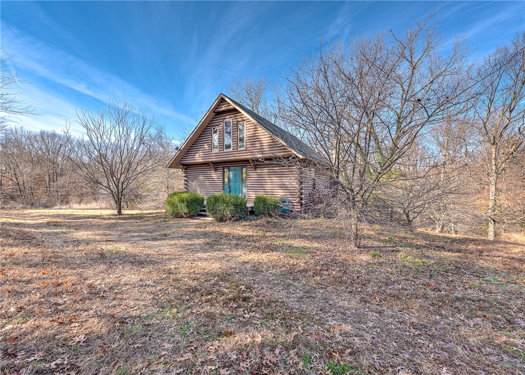 This custom built solid oak log cabin home located on the outskirts of Pea Ridge provides a unique living space. The main floor has an open concept with the kitchen and living room areas, great for entertaining! The oak walls and real wood floors add warmth to the room and the sliding door accesses the large wooden deck overlooking the 1.79 wooded acreage. The 2nd level is the primary suite with a bedroom, bathroom and private balcony. The walk-out basement has a large multi-purpose room, laundry room, closets, bathroom and a covered patio. It would make a great bedroom suite or second living room for family members or overnight guests.