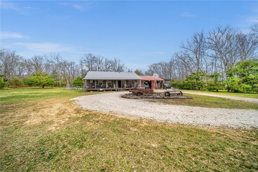 A unique opportunity to own 56 acres of serene Arkansas countryside just 20 minutes from town. This rustic 1,920 sqft home offers a perfect retreat for outdoor enthusiasts seeking tranquility without sacrificing convenience. The property features 4 cleared acres and 12 wooded acres, providing ample space for exploration, gardening, or enjoying nature. An additional 40 acres to call your own is a short distance away. Built in 2014, this home boasts 4 versatile rooms, including a master suite with a walk-in closet and private bath. The open floor plan connects the family room, warmed by a cozy wood stove, to the dining area and spacious kitchen with a pantry. Additional amenities include a covered front porch, a 32x30 attached carport with extra storage, and an unfinished attic awaiting your touch. Outdoor living is enhanced by gardens, a backyard fire pit, a horseshoe game area, and a 100+ yard shooting lane. Experience the best of country living with modern comforts in this Arkansas homestead. See MLS 1302187.
