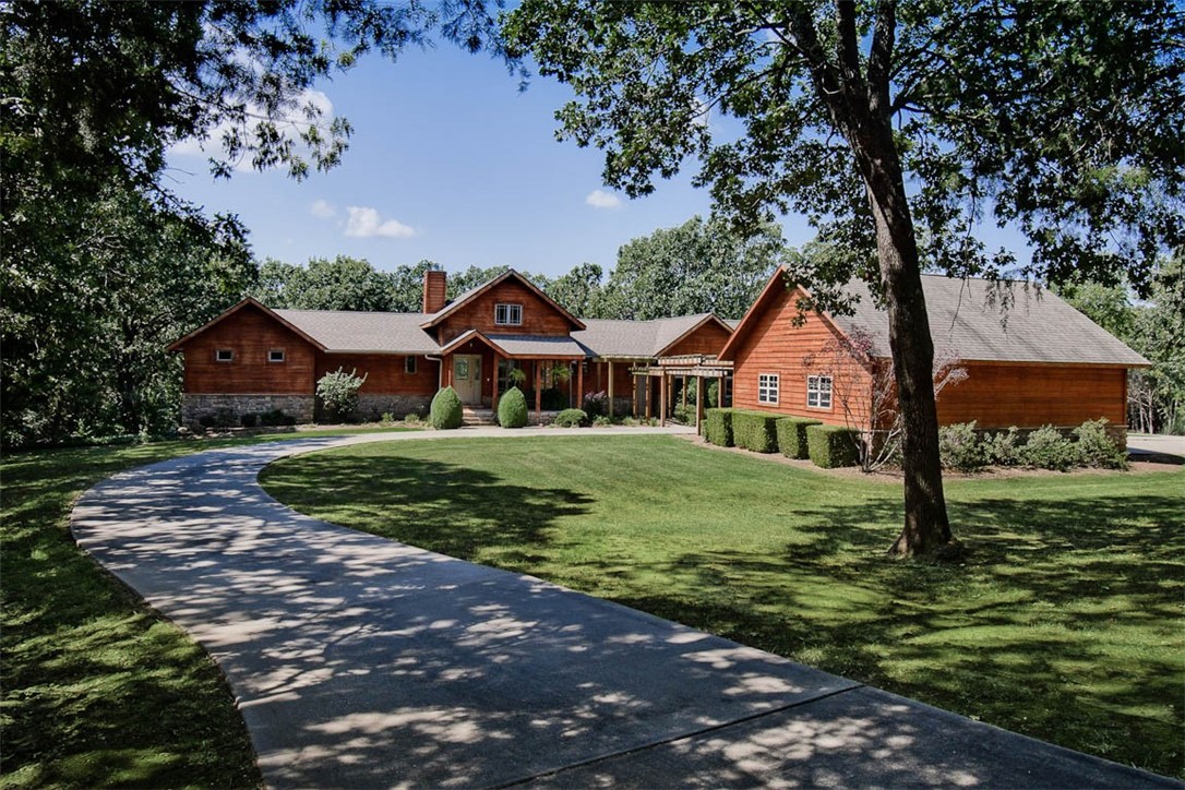 This stunning two-story cedar-sided home sits on 6 beautifully landscaped acres with mature trees and a circle drive. Spanning 5,000 SF, it features an open floor plan with a 16-ft ceiling in the living room, a wood-burning fireplace, and views of the sparkling pool. The main level includes a luxurious master suite, guest bedroom, office, two full baths, and a half bath. Granite countertops enhance the kitchen and baths, with wood, tile, and carpet flooring throughout. The lower level offers two bedrooms (possible third), a second kitchen, and spacious living area—ideal for guests or in-laws. Outdoor highlights include a large pool, pool room with bath and changing area, outdoor kitchen, and pickleball court. Additional amenities: attached garage, two detached garages, and wooded trails. The front yard offers a peaceful, park-like setting, with extra acreage available for expansion. A private, amenity-rich retreat in a picturesque setting. Agent owned.