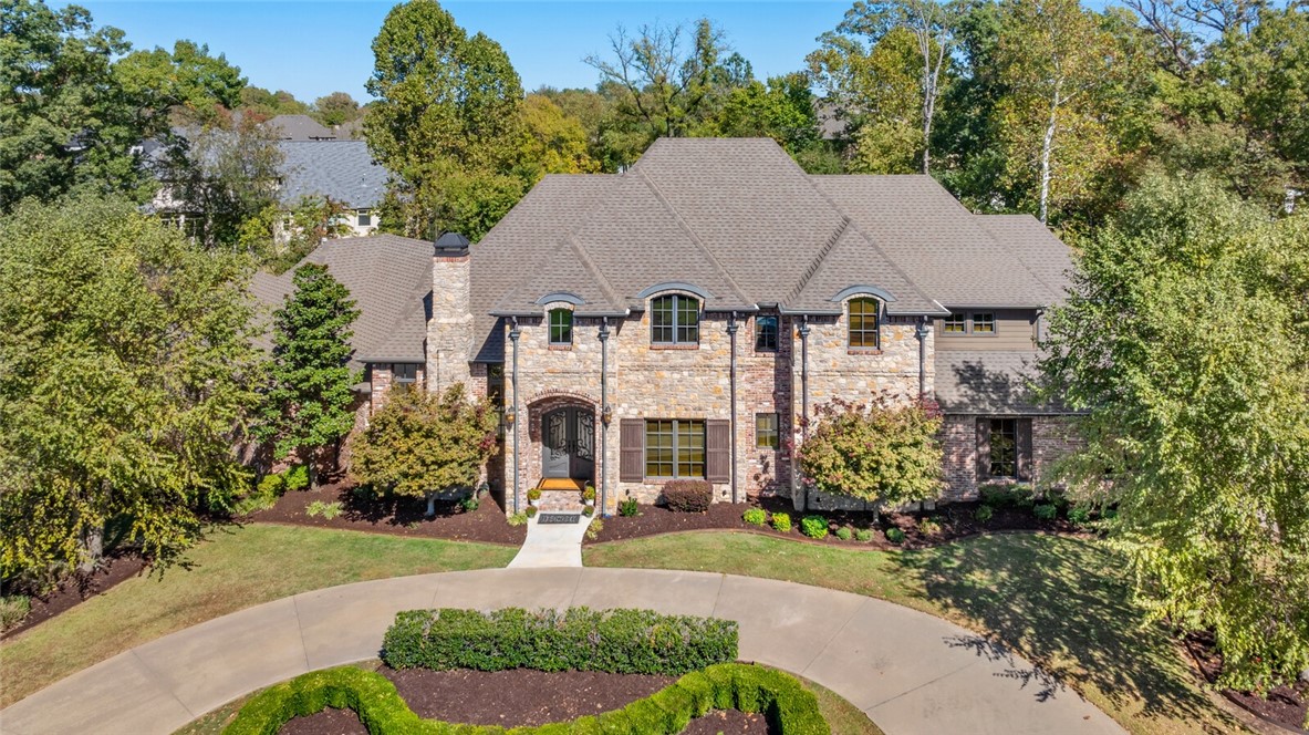 Resort style 5,540 sq ft estate in Pinnacle Country Club on a private 0.78-acre cul-de-sac in Bentonville School District. This fully updated home features natural stone & reclaimed brick exteriors, 5 en-suite bedrooms, 5 full & 2 half baths. Enter through French doors to a stunning foyer with round staircase, executive office, & formal dining. The open-concept layout connects the gourmet kitchen with top-tier appliances, custom rich cabinetry & large island to spacious living & dining areas with vaulted ceilings, exposed wooden beams & stone fireplace. Main level features 2 bedrooms, including a primary suite with private pool access & spa-like bath with dual walk-in closets. Upstairs: 3 bedrooms, theater/game room with savant controls & additional office. The backyard boasts a heated Gunite pool, swim-up bar, spillover spa, fireplace & outdoor kitchen. Additional features: 4-car+golf cart garage, updated multi-room Sonos sound system, wine room, wet bar, central vac, whole-house water filtration & storm shelter.