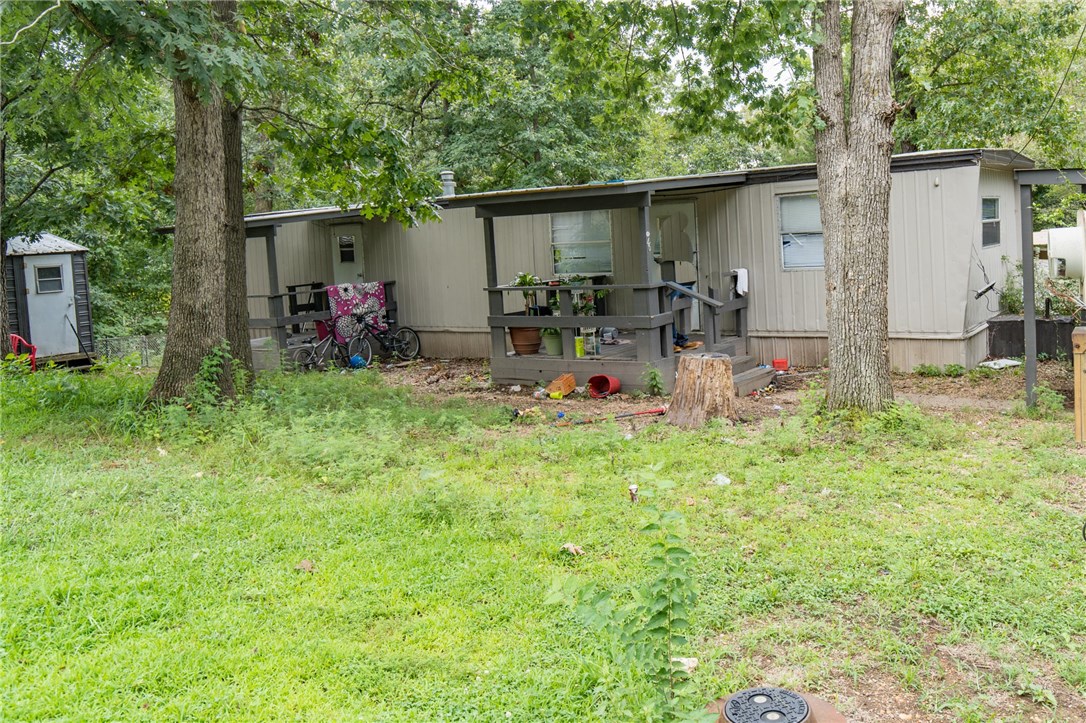 Investor's Delight! This is 1 of 4 units for sale in this mobile home neighborhood; purchase together or individual. Includes appliances, carport, large storage building. Private location nestled among trees, yet just few minutes from Hwy 71 or I-49. Strong/consistent rental history $585 month. Current owner pays POA fees & water bill. Tenant pays electric & propane. No sewer bill; on septic. Propane for central heat, cooking, water heater. This unit is occupied; another is vacant & available for showings