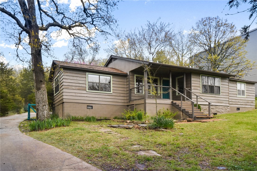 Come feel at home in this wonderful Southeast Fayetteville neighborhood! Quaint 2 bedroom, 1 bath home sitting on a 0.4 acre lot. With over 1,000 sqft. inside, wood floors and large windows with park-like views, this home offers serenity while being minutes from the UofA. Just off the living room you’ll find the kitchen with sitting area, subway tile backsplash, appliances to convey and lovely cabinetry. You will find a spacious bedroom and bath that has been newly remodeled with a modern aesthetic and double sink. Keep warm by the free standing fireplace or enjoy time outdoors under the covered patio! This home is conveniently located near grocery stores, I-49, Mt. Sequoyah Trails and the UofA. Fantastic location!