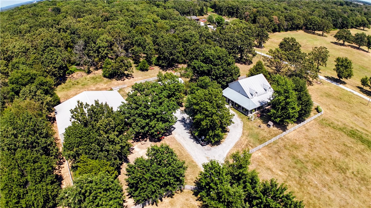 Two-story farmhouse on 15 acres! This 3-bed, 3-bath, 2,794sf home blends classic charm with rural serenity. The welcoming wrap-around porch leads into an open floor plan, perfect for entertaining. Kitchen has granite, gas cooktop, double wall ovens, dishwasher, & microwave/vent. Breakfast nook area & dining room. Primary bedroom, bath, & utility downstairs with fireplace in LR. Upstairs, you'll find a flexible bonus room, full bath, & guest rooms. Metal roof & vinyl exterior. The property is a mix of pasture & wooded acreage with pipe fencing, apple, & pear trees. 2 Shops with concrete floors & electric (one has 110), & a barn with six bays on each side provide extensive space for cars, projects, & storage. Basketball court with goal. Corrals convey. Frost-free hydrants. Located on a paved road just outside of town with a circle drive. City water, natural gas, & septic system. HVAC-appx 4yrs. Hot tub conveys. Survey needed-15 acres m/l.
