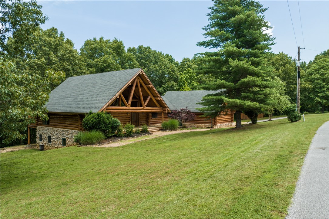 It's like your own private Whistler in Bentonville! This handcrafted, custom Log Home on five acres is a mountain biker's paradise with a private jump line designed by Rogue Trails (be sure to watch the video) and located just a mile as the crow flies from Handcut Hollow. Lodgepole Pine Logs from Canada combined with River Rock veneer exude the perfect mountain feel. Just 10 minutes from Downtown Bentonville. Open floor plan features a great room with a vaulted Aspen ceiling and stone fireplace; well-appointed kitchen with custom maple cabinets, high-end appliances; and loft that makes for the perfect home office. Walk-out basement with bonus room and wet bar leads out to a lower-level stone patio and fire pit. Mechanical room outfitted with indoor skate/bike park is also well-suited for a workshop with tons of storage. Enjoy an expansive view from multiple decks. Wooded acreage features dogwoods, seasonal morels, wet weather waterfall and an abundance of wildlife.