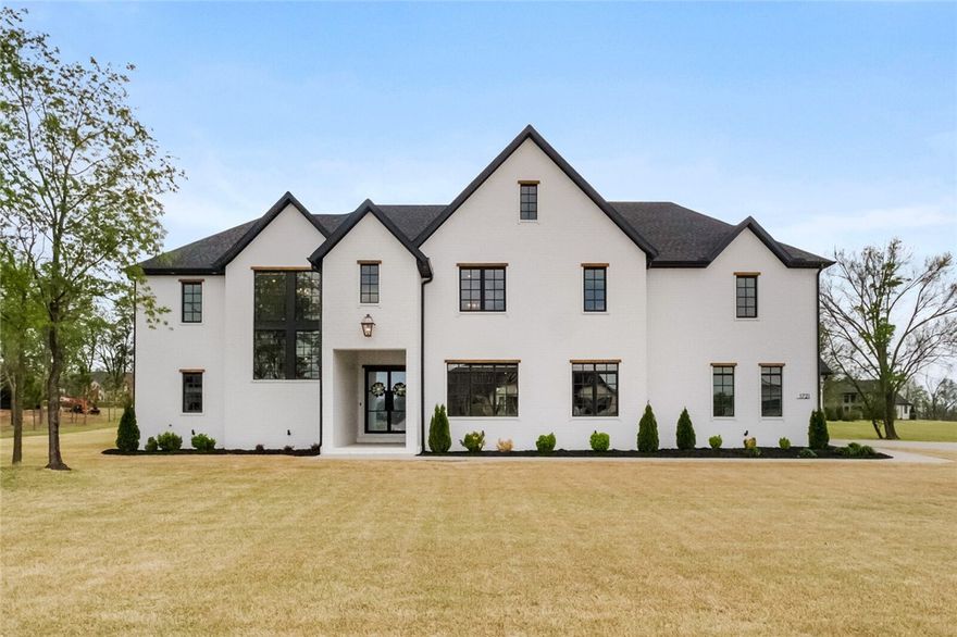 Tucked inside a prestigious West End gated neighborhood and zoned to top-rated Bentonville schools, this stunning custom estate sits on over an acre and exudes luxury at every turn. Offering 5 spacious bedrooms, 5 full bathrooms, 1 half bath, and a 3-car garage, this home blends elegance with functionality. The soaring entryway showcases a grand staircase framed by dramatic black-trimmed windows, setting the stage for the refined interiors. The open-concept kitchen and living space features quartz countertops, designer lighting, and high-end appliances—perfect for entertaining. Additional highlights include a formal dining room, private office, media room, and an oversized attic with potential to finish out. The luxurious primary suite is a true retreat, featuring dual vanities, a walk-in shower, a soaking tub with scenic views, and a spacious walk-in closet with a center island. Enjoy outdoor living on the covered patio overlooking the expansive yard. This home defines elevated living in Northwest Arkansas.