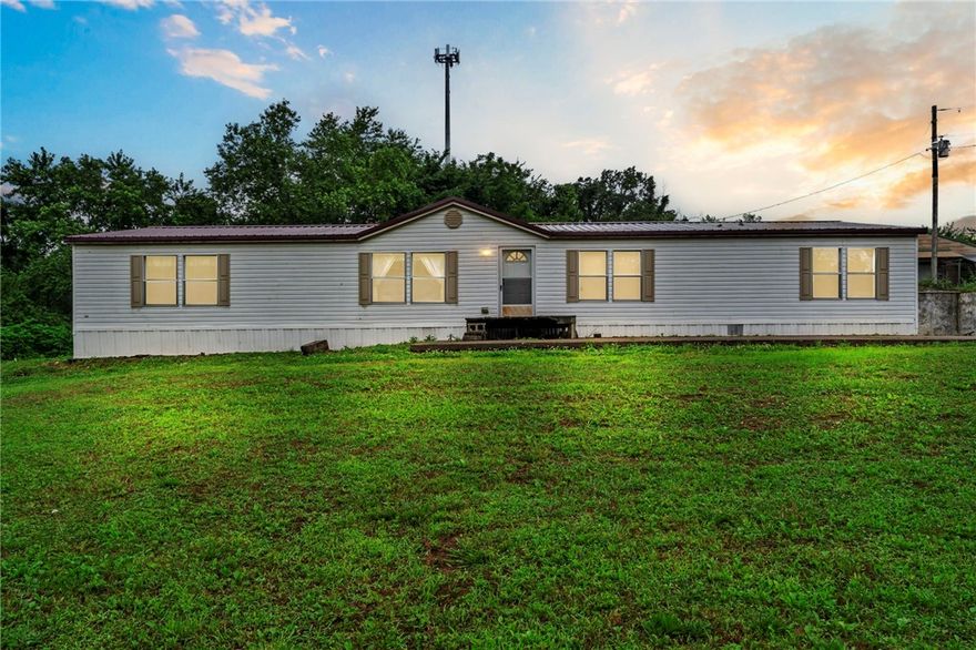 Just 20 min from XNA and 30 from downtown Bentonville, this 6.45-acre property offers endless possibilities and stunning scenic views. With the home facing east, enjoy peaceful mornings and unforgettable sunsets from the west. The spacious 4 bed, 2 bath double-wide features two living areas and plenty of room to stretch out. An outbuilding provides extra storage, and the inoperable chicken houses (since 2019) offer repurposing potential. New roof in 2024 and HVAC replaced in 2011. Whether you're dreaming of a mini farm, a peaceful retreat, or building new, this land is full of opportunity. Sold AS-IS.