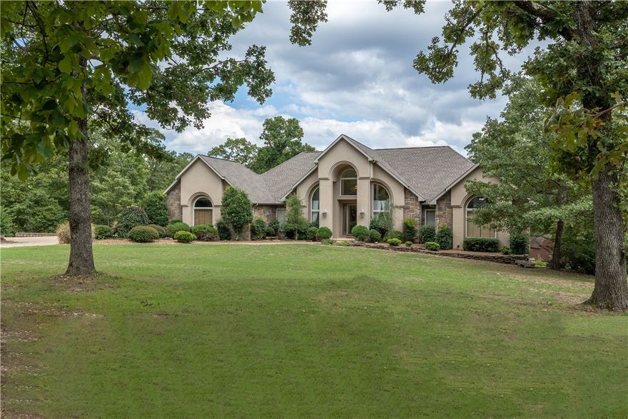 Welcome home to your 1 Owner, Custom built retreat thoughtfully placed amongst  7+ acres of all the beauty & hardwoods the Ozarks have to offer.  Quietly placed at the end of a cul-de-sac street ensuring premium privacy & guaranteed relaxation.
Yet this home, located in Highlands Estates, is only 2 miles to I-49 & approx. 5 minutes to 18 holes of championship golf like Highlands & Scottsdale Country Clubs.  Is the lake life your game ?  Loch Lomond, the largest private lake in All of NWA is just a few minutes away as well. And if you haven’t heard, Bella Vista is now home to one of the top mountain biking trail systems in the entire U.S.  And, you can be on these nationally renowned trails, in mere minutes.
Home boasts over 7,000 heated sq ft, thanks to the radiant heating system in the 2500 sq ft shop.  This custom building has it’s own RV bay plus the capacity to fit 6 MORE CARS as well. Wow!  This shop has so much potential for other uses as well. 4th BR getting closet remodel.