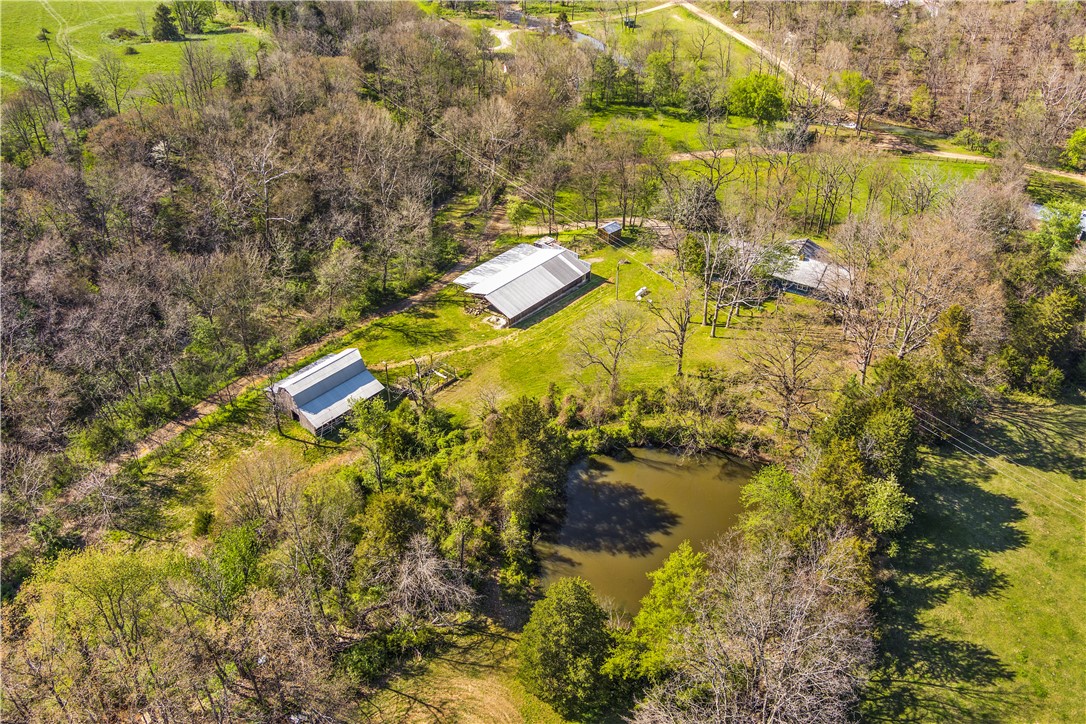 Picturesque and peaceful, this property is perfect if you are looking for a gorgeous home in the country. Situated on 9.68 beautiful acres, this home has 3 nicely sized bedrooms and 2 bathrooms in the main house. The kitchen & living room are open with a rustic feel and feature a charming stone chimney and woodstove to keep you cozy in the winter. The attached In-law suite is freshly remodeled in 2021 & has 1 bedroom, a partial kitchenette, 1 bathroom, and can be accessed through the house or from it's own outside entrance. The property has several springs, large spring fed pond, wet weather creek, 2 story 40x40 barn, large shop with a concrete pad and steel trusses, storage shed, and a large raised garden bed. Many updates have been done including fresh paint on the exterior & kitchen cabinets, updated hall bathroom, Culligan water softener, New HVAC in 2016, and water heater in 2020. Enjoy living your best life while relaxing on the large screened in porch, enjoying the views, or fishing in the pond!