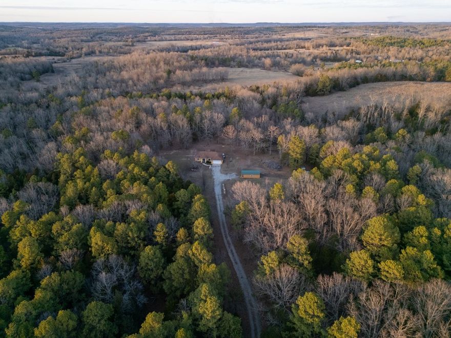 62± acres on Elizabeth Road in Viola, AR with a 1,440 sq ft 3BR/2BA home plus 1-car garage built primarily of split-face concrete block. Winding gravel drive through mixed hardwood, pine, and cedar timber opens to a private yard with 30x20 shop, 24x12 storage building, chain-link dog pen, and a year-round spring. Valley behind home offers potential food plot area with deer and turkey sign. Open-concept kitchen/living with tile floors, solid wood cabinets, solid-surface countertops, and wood-burning fireplace. Primary bedroom has wood floors and walk-in closet; primary bath features tile-floor with shower. Guest bedrooms have wood floors and closets; guest bath has tub/shower combo with tile flooring. Utilities include private well, NAEC electric, NEXT Fiber internet, septic. Electric HVAC and electric water heater. Appliances convey: refrigerator, oven/range, washer, dryer.