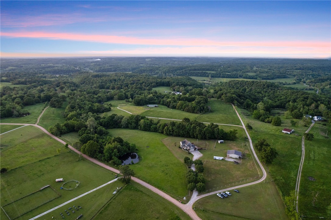 Experience this breathtaking landscape of over 21 pristine acres offering a 1,440 sqft 3 stall barn (w/ individual paddocks) w/ tack room, & pull through hay storage; 15x21 Lean-to w/ 100 hay bale storage; private pond stocked with Bass, Catfish, & Bluegill; Spacious Outdoor Plumbed Kitchen fully equipped to host any outdoor event featuring a large gas grill, restaurant style vent-hood, stainless steel refrigerator, built-in waste bin drawer, wired for sound, A/V receiver, outdoor TV, hot tub, Trex® Decking, pergola, & a custom concrete fire pit. Step inside this oasis offering solid oak flooring, tons of natural light, & views for days! Recently updated kitchen w/ stunning Quartzite, clear view cabinetry, built-in wine rack, & more! Make your way up the custom staircase to explore the sizable primary suite w/ gas fireplace, deep soaking tub, & private office. Home has hardwired 14.5kw whole house Generac Generator, 6 person in-ground steel storm shelter & New Roof (5/25)! Also listed ML #: 1306464