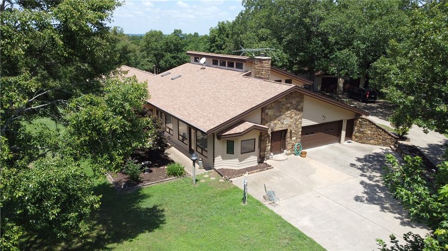 Rare Opportunity! Enjoy estate living on 38.20 beautiful acres boarding Hobbs State Park. The land has several clearings for possible future building sites. The custom designed/built Stitt energy efficient one owner home, features a living room with stone fireplace, open floor plan with natural light, and primary bedroom suite on the main level. Upstairs is an open landing overlooking the main level with two bedrooms and full bath. Off the large south patio is the 1,150+ sq. ft.  heated and cooled cedar great room with the 36'x15' indoor pool (not included in the MLS sq. ft). Solar water heating system. New roof in 2023. All appliances including extra freezer, washer and dryer convey. Four excellent outbuildings. From a private paved drive it's a scenic 15-20 min to downtown Rogers. Bring your vision - This property is ready for it's new owners!
