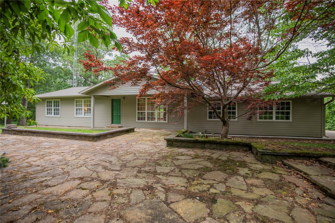 The most requested kind of real estate in NWA- a house with a little bit of land! And all on 1 level! With over 2.5 acres, this well-maintained home is nestled at the end of a quiet cul-de-sac with views of horses grazing in the pasture. Enjoy the serenity of nature on the expansive back deck or flagstone front patio surrounded by mature trees, established flower beds, and plenty of birds chirping in the background! The home has original hardwood floors-- and no carpet anywhere in the home! Got an itch for gardening? There are raised beds and plenty of room to expand them! The interior has neutral paint, adorable kitchen complete with Lazy Susans, gas range, and tons of cabinet space! This isn't your average 3 bedroom house- located right off the garage is a heated/cooled bonus space with its own entrance- great for work from home! The spacious living room includes a wood burning fireplace and large windows bringing nature inside! An ideal location: 5 miles to I49, 14 mi. XNA, & 12 miles to U of A. New roof in '23!