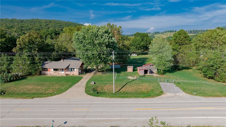 Flexible-use fixer on 2.38 acres in Brentwood. Bones are good on this all-brick ranch, one level, house with 3 bedrooms and 1.5 bathrooms. Perfect for many uses – residential, home school, hobby farm, commercial or future development. Original hardwood floors with abundant built-in storage. Bright sunporch and big bonus room. Huge, oversized 984 sq. ft. garage with office is not included in the total square footage. Newer roof with updated HVAC and vinyl windows. Flat, usable acreage is fully fenced with paved driveway and gated entries. Land is mostly cleared with barn, outbuilding and old well house. Located 12 miles south of Fayetteville. Sold AS-IS.