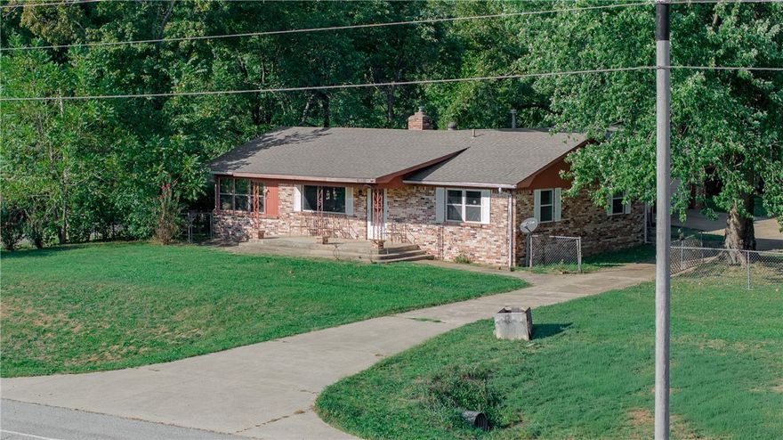 Flexible-use fixer on 2.38 acres in Brentwood on the Boston Mountain Scenic Loop. Bones are good on this all-brick ranch, one-level house with 3 bedrooms and 1.5 bathrooms. Perfect for a variety of uses – residential, home school, hobby farm, commercial or future development. Original hardwood floors with abundant built-in storage. Bright sunporch and big bonus room. Oversized 984 sq. ft. garage with office (not included in the total square footage). Newer roof and 2020 HVAC. Flat, usable acreage is fully fenced with paved driveway and gated entries. Land is mostly cleared with barn, outbuilding and old well house. Ozarks Electric with Ozarks Go and Winslow water. Located 12 miles south of Fayetteville between West Fork and Winslow. Sold AS-IS.