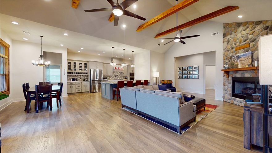 Framed by stone and cedar, this modern rustic beauty stands out with beautiful design touches. This one level, open floor plan features cedar beams, wood floor, a stacked-stone gas log fireplace. An eat-in kitchen boasts a large island, 5-burner gas stove with pot filler, a pantry & coffee/wine bar area. The primary suite is a true retreat with a whirlpool tub, walk-in shower with dual heads, dual vanities & a spacious closet with built-ins. There are 3 more bedrooms, 2 additional full baths PLUS an office. A covered patio provides great entertaining space. Enjoy cool nights sitting by the outdoor stone fireplace or grilling steaks at your outdoor kitchen. Highlights: tankless water heater, exterior uplighting, irrigation system, central vacuum & 3-car garage with epoxy floors. Cook smores in fireplace or picnic at the community pavilion. Ideally located near I-49, XNA, Bentonville West High, Coler MTB Preserve, and WMT Global Campus—all within 10 minutes. One owner home. See Feature Sheet for even more information
