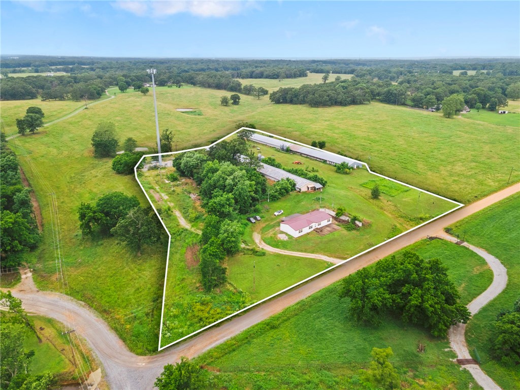 Just 20 min from XNA and 30 from downtown Bentonville, this 6.45-acre property offers endless possibilities and stunning scenic views. With the home facing east, enjoy peaceful mornings and unforgettable sunsets from the west. The spacious 4 bed, 2 bath double-wide features two living areas and plenty of room to stretch out. An outbuilding provides extra storage, and the inoperable chicken houses (since 2019) offer repurposing potential. New roof in 2024 and HVAC replaced in 2011. Whether you're dreaming of a mini farm, a peaceful retreat, or building new, this land is full of opportunity. Sold AS-IS.