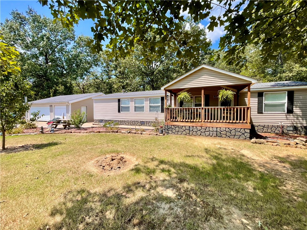 Enjoy country living just minutes from Dardanelle in this 3BR/2BA home on 6 acres. The open-concept layout features a spacious living room with cathedral ceilings and fireplace, a dining area, and a kitchen with island seating. The split floor plan offers a private master suite with walk-in closet, double vanity, jetted tub, and separate shower. Extras include a large walk-in pantry, oversized laundry room with space for a freezer, and both front and back covered decks perfect for relaxing. A 3-car detached garage/shop provides room for projects and storage. The property boasts fruit trees, mature shade trees, and plenty of space for pets, chickens, or kids to roam.