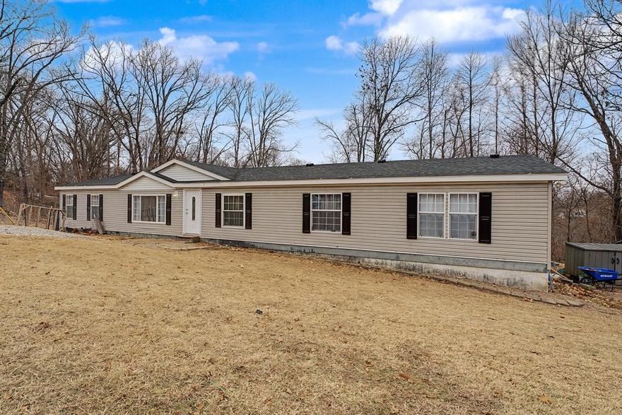 Come check out this well-kept, updated manufactured home with a permanent foundation sitting on 3 quarter acre lots in Bella Vista! Conveniently located just 10 minutes to the bike park, 6 minutes to Tanyard creek, and a 15 minute drive to Mercy and I-49! This 2,280 square foot home features a functional split floor plan, open kitchen and dining area, built in desk and storage, and a large bonus room with a wood-burning fire place great for a second living space, home office, or game room! Current owners added a fresh coat of paint and new flooring through out, painted cabinets, updated shower in primary suite, new deck and cleared yard + 17 trees. The roof was replaced by previous owners in 2016 along with the range (2021) and dishwasher(2022). Detached storage unit conveys, and refrigerator + all appliances convey with acceptable offer! No POA!