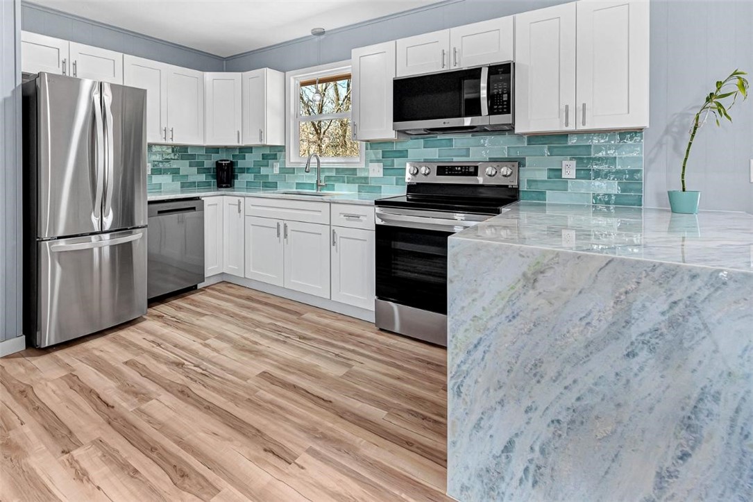 Freshly remodeled with high end finishes, a brand new roof and gutters, new appliances (including refrigerator), new windows, Shadow Storm hard marble countertops and waterfall, waterproof LVP flooring, and a gorgeous tile shower and tub surround. This home sits on a fairly level lot and is surrounded by mature trees. The front yard is nearly all rock so very low maintenance. As a bonus this home features a 680 SQFT heated and cooled basement with potential to be your dream workshop. The basement has several outlets and plumbing in place for a sink. The Flo-Ride trail is less than 60 seconds from your front door via bike. Enjoy some of the best biking and hiking in Bella Vista without ever hopping in a car! Property is agent owned. RD eligible.