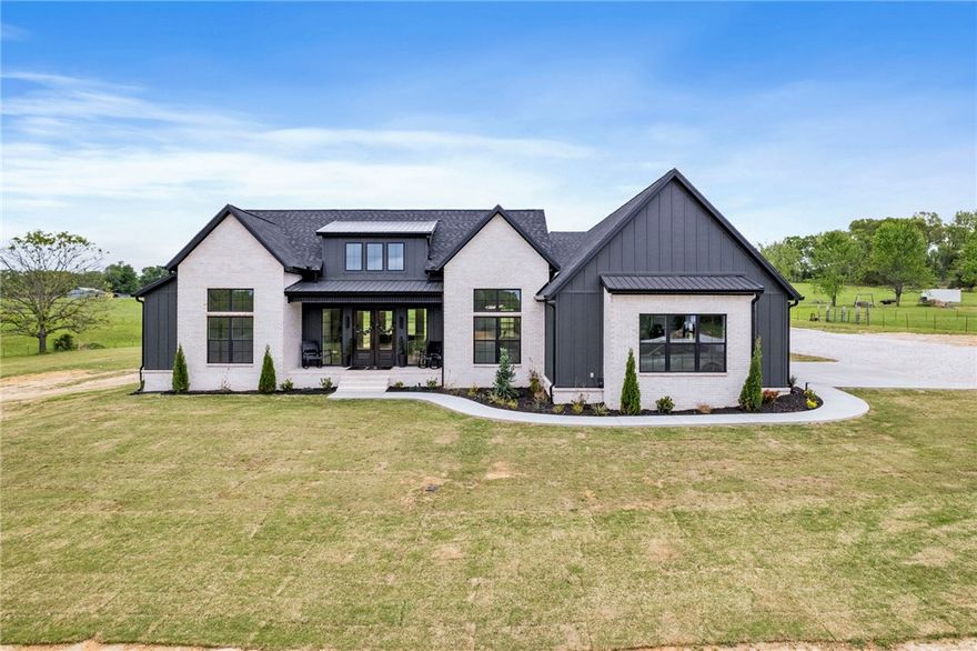 Welcome to your own slice of heaven in peaceful Garfield Arkansas. Located just 20 minutes to the Walmart Home Office, this new construction home is sure to impress! Sitting on 4.68 private acres, this custom built home is all on one level and has covered front and back patios. Professionally landscaped with a side load oversized garage, the overall appeal on this black and white modern home is what buyers dream of. You also get a 1500 sq ft Metal Shop with dedicated 200 amps and backup generator hookup and EV hookup. Walk into double front doors with soaring ceilings, gas fireplace, all wood flooring throughout, custom kitchen with an attached scullery kitchen, quartz countertops, and a large dining room with a featured wood wall. Primary suite sits on one side of the home with a huge walk in closet, soaking tub, large shower, and connects to your impressive laundry room. The other side of the home features 3 spacious bedrooms all with walk in closets and bathrooms. Half bath for your guests right off the living.
