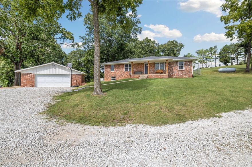 Set on just over 21 acres, this updated home has timeless charm & privacy with Beaver lake views—partial in summer, full vistas in fall & winter. The homes updated interior features 2904 sq ft with 3 bedrooms, 2 bathrooms, solid hickory flooring, new doors & trim, LED lighting & fully remodeled basement with bonus room & recreational flex space. Living room centers around a gas log fireplace & eat-in kitchen includes stainless steel appliances & bar for casual dining. Thoughtful upgrades abound: new tankless hot water heater, new roof on home & garage, whole-home generator w/500-gallon propane tank, Tesla charger, 30 amp RV service, expanded driveway, added culverts & fencing, new landscaping & sod, cedar-wrapped porch columns. Outdoor, a fire pit, trimmed canopy trees, & open acreage create a park-like retreat. Minutes to town & public boat launch, this property offers a rare combination of privacy, beauty, convenience & lake life. Commercial 60 inch zero turn convey with property.