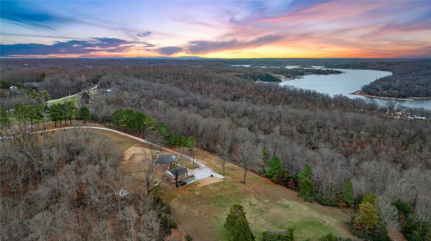 Set on just over 21 acres, this updated home has timeless charm & privacy with Beaver lake views—partial in summer, full vistas in fall & winter. The homes updated interior features 2904 sq ft with 3 bedrooms, 2 bathrooms, solid hickory flooring, new doors & trim, LED lighting & fully remodeled basement with bonus room & recreational flex space. Living room centers around a gas log fireplace & eat-in kitchen includes stainless steel appliances & bar for casual dining. Thoughtful upgrades abound: new tankless hot water heater, new roof on home & garage, whole-home generator w/500-gallon propane tank, Tesla charger, 30 amp RV service, expanded driveway, added culverts & fencing, new landscaping & sod, cedar-wrapped porch columns. Outdoor, a fire pit, trimmed canopy trees, & open acreage create a park-like retreat. Minutes to town & public boat launch, this property offers a rare combination of privacy, beauty, convenience & lake life. One season electric ATV & Commercial 60 inch zero turn convey with property.