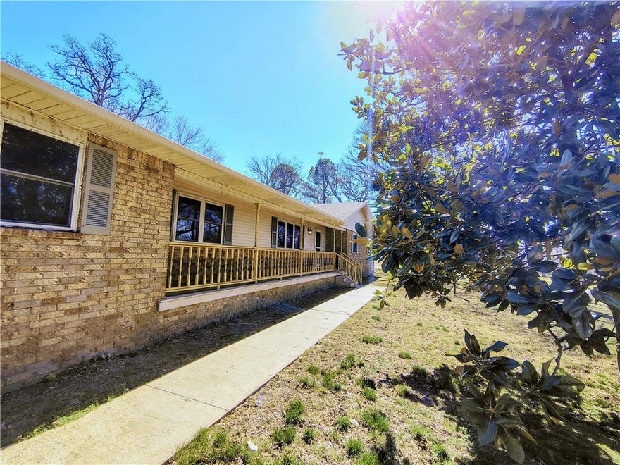 Enjoy the perfect blend of comfort, privacy, and convenience on this 1.16-acre corner lot just outside town. Surrounded by mature trees and wide yards, the property offers peaceful west-facing sunset views with a quiet, rural feel minutes from amenities.

With over 3,200 square feet, this home features 4 bedrooms, 3 full baths, and multiple living spaces ideal for relaxing or entertaining. Two rock fireplaces add warmth and character throughout.

The kitchen features granite countertops and connects easily to both formal and casual dining spaces. Additional highlights include a tile-surround jacuzzi tub, reinforced safe, and oversized mudroom/utility area with extra refrigerator. Washer and dryer convey.

Outdoor living includes a covered front porch, covered back patio, and rock patio perfect for enjoying the scenery. Located less than five miles from downtown Springdale, dining, shopping, and the Razorback Greenway, this property offers exceptional value for acreage and square footage in a prime location.