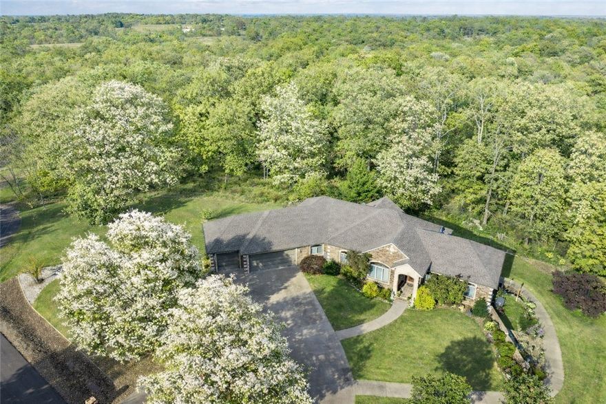 Close to Branchwood- pickle ball, walking trails, indoor swimming gym,  Branchwood Nature Trail and more!. This O.A.K.–built home offers exceptional quality with 11’ ceilings, solid oak floors, poured-concrete foundation, and rare privacy on three lots totaling .98 acres. Enjoy stargazing from your deck, pick fruit from mature plants, or simply unwind in total seclusion. Inside, you’ll find two fireplaces (including a brick-surround Kozy Heat gas log), a wall of windows overlooking the patio, and 1,100+ sq ft of climate-controlled storage plus a 3-car garage with a concrete circular drive and full house back-up generator. The lower level is ideal for multi-generational living with a large wet bar, full-size refrigerator, storage under the stairs, full bath, spacious bedroom, and interior workshop with workbench, utility sink, and HVAC. Double doors open to a private patio. Close to lakes, golf, and walking trails—this home blends comfort, function, and nature.