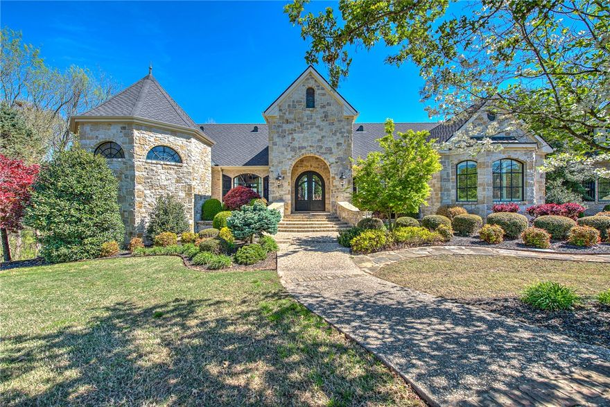 Welcome to an extraordinary French Country estate where luxury, privacy, and breathtaking views come together on 2.3 acres in the exclusive gated Beau Chalet community—just minutes from XNA. This award-winning 5,468 sq ft masterpiece, designed by Boyce McQuay and built by Steven Pillars Contracting, makes a lasting impression from the moment you step through its grand iron entry. Inside, you’ll find three stunning living areas, a veranda-access dining room perfect for entertaining, a private executive office with fireplace, and a chef-inspired kitchen. With 4 bedrooms, 4.5 baths, and a private storm shelter, comfort meets peace of mind. Upstairs offers a spacious bonus room, bedroom, full bath, and storage. Step outside to your own private retreat—featuring wraparound covered patios, a resort-style pool with waterfalls, lush landscaping, and a custom fire pit for unforgettable evenings. A Parade of Homes Award winner, this one-of-a-kind residence captures timeless elegance and elevated living in every detail.