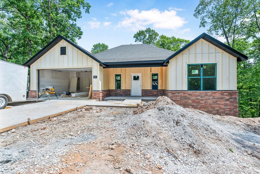 *Agent Owned*  Welcome to your NEW HOME on a larger .43 acre wooded lot. Northeast Bella Vista location in Bentonville Schools and backing up to "Flo Ride" - Part of The Back 40 Trail System - Nearly 40 miles of trails designed and built for mountain biking but also open to use by pedestrians! Extended covered deck overlooking mature trees and beautiful views. Interior features vaulted living room ceilings, modern electric fireplace, and a light colored luxury vinyl plank flooring throughout. Large kitchen island with extra storage, white quartz counters, and stainless steel appliances. Master bath has fully tiled shower and dual vanities. Dedicated laundry room with built-ins. Hot water recirculation system. One year builders warranty. See photos and MLS attachments for plans and survey. Construction will be completed and ready for move-in by early to mid June!