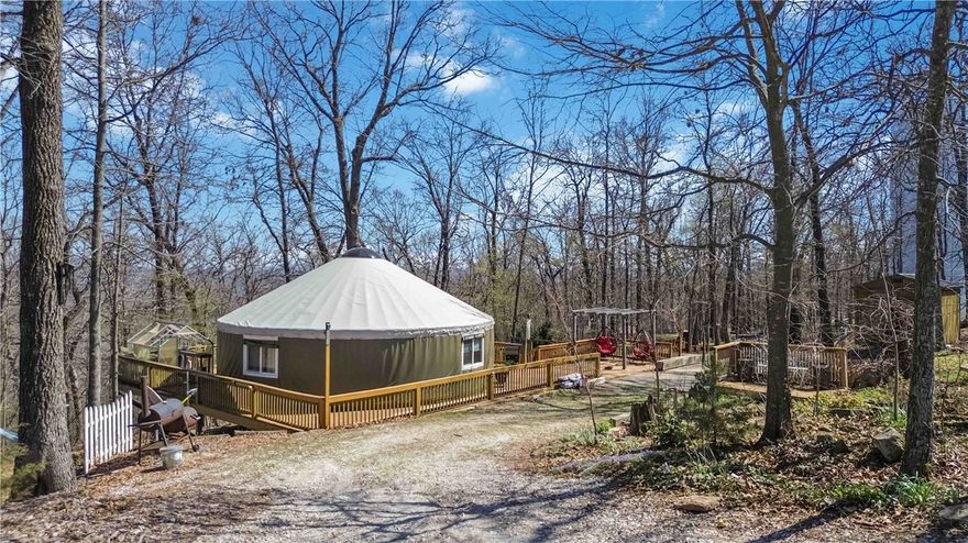 Tucked into the natural beauty of Northwest Arkansas, this one-of-a-kind 30 ft Pacific Yurt offers the perfect blend of a private retreat and income-producing opportunity. Thoughtfully upgraded with wind and snow protection, a UV-protected dome, energy-efficient windows, and a brand-new premium vinyl tarp and side cover, it’s built for year-round enjoyment.
Inside features a full kitchen with dishwasher and disposal. Select furnishings convey, making it easy to step in and start enjoying or renting right away.
Outside, enjoy seven decks, two water features, two fire pits, an outdoor shower, and a pre-wired hot tub pad. A separate RV pad with electric, water, and septic adds flexibility for guests or additional income.
Backing to Devil’s Eyebrow habitat and just minutes to Beaver Lake, Rogers, and Eureka Springs. Featured in Citiscapes 2022 and currently operating as a successful Airbnb.