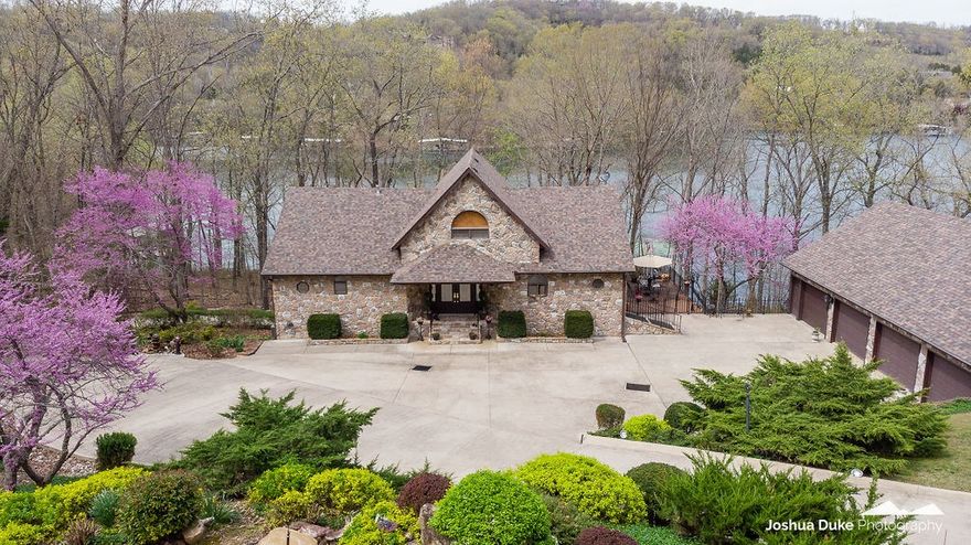 PERFECT LAKE FRONT home. Easy almost flat walk (100') to your private 2 slip dock w/lifts & swimdeck.  Immaculate 4000sf custom built home. Handicap accessible with elevator. Floor to cathedral ceiling windows. Open floor plan. Living, master, kitchen, utility room on main level. 3rd level loft br w/ bath. Lower level (party central) Huge granite bar with custom seating, specialty lighting, ice machine, frig, sink. Large family room w/FP. Huge bunk room w/spa. Could be 2nd master BR or break off to 2 brs. Walk-in double shower. Space for game or pool table. Office/bedroom. Access the 1344 sf. 4 car detached heated/cooled garage through the basement level workshop/storage/living quarters. Garage has full bath and attic storage. Home & garage have Petra stone exterior and iron soffits and iron fencing around decking for maintenance free care. Beautifully landscaped w/ accent lighting.  Ample parking on custom cement approach to home which includes drainage system for home and driveway feeding into the lake. Come see!