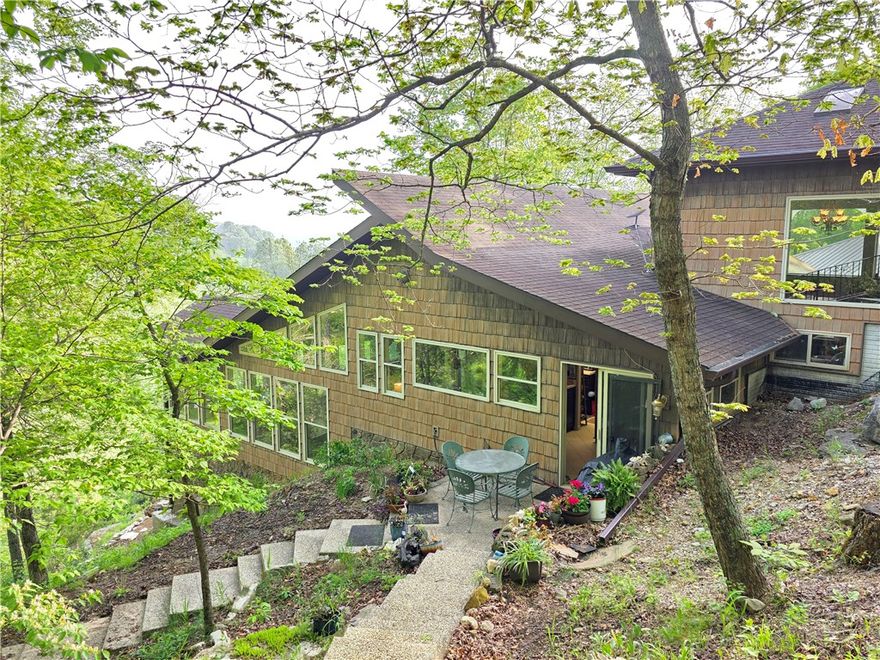 Escape to your own UNIQUE private retreat with this unique 2BR/2BA, 2358sf, multi-level secluded mountain cabin nestled on approximately 13 +/- ac, completely chainlink fenced & electric gate opener, adjoining and overlooking the stunning, year-round Crooked Creek, on asphalt & only 5 min to Harrison! Surrounded by natural beauty, this one-of-a-kind property offers privacy, captivating views, and a limestone bluff trail leading from your patio down to the yr-round Crooked Creek. Designed to maximize light and connection with the outdoors, the home features an airy atrium with a beautiful painted wall mural and skylights, expansive windows that frame the breathtaking scenery, and a balcony overlooking the view and creek! The kitchen includes a butler pantry and there's ample storage throughout the home and even a storage cellar/shelter. In addition to the main residence, the property includes an attached carport, detached structure of approximately 576 sf storage area, workshop and wellhouse.