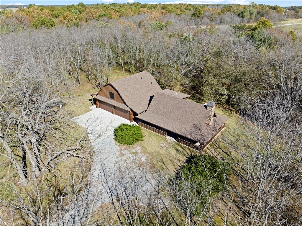 This true log cabin with guest house is the epitome of rural living at its finest! Located in the exclusive gated community of The Cabins at Big Springs, this incredible property is just a few minutes from Gravette & offers easy access to I-49 for a short drive to Bentonville & Rogers. The main cabin features a stunning rock fireplace & open, yet cozy, living room/dining space/kitchen. Main cabin also houses two bedrooms, two full baths, & is finished with real wood floors, walls, & ceilings to embody the true log cabin aesthetic. Outside, soak up nature from your wrap-around porch or sit on the deck that overlooks a seasonal creek. Adjacent to the main cabin is a guest house added in 2020. It provides an additional 1205 sq ft of living space including a heated & cooled workshop plus a four-car garage. Property owners have access to 120 acres of common land, stocked fishing pond, event barn, park, & pavilion as well as access to Bella Vista lakes & golf courses! POA maintains owner yards for minimal maintenance.