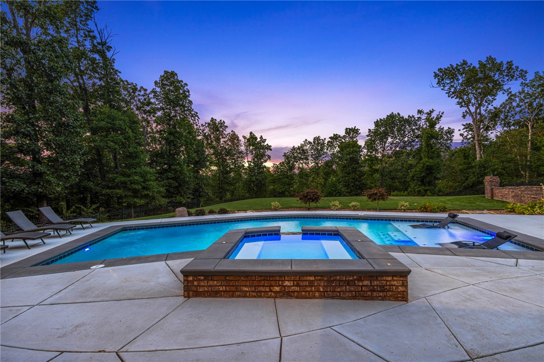 Oak Tree Estate home on 1.39ac lot, newly added pool & outdoor living space, 5 Beds plus bonus space, home office & more! Spacious driveway & Foyer entry welcomes you. Formal dining w/ accent wall. Living room has fireplace w/ built ins, large windows looking out to your private yard & wooded setting, wood floors, and open to kitchen. Kitchen has beautiful coordinating granite counters & backsplash, large island w/counter seating, 6 burner gas range w/ pot-filler & large pantry. Home office w/full wall-built ins. Guest suite w/attached bath & WIC on main. Primary suite is a spacious bedroom w/sitting area, spa-like bath has gorgeous soaking tub w/ wraparound walk in shower! Downstairs is the second living area. 1 guest room has attached bath. 2 additional guest rooms share jack & jill bath. Access to the large, covered patio on lower-level w/built in radiant heaters, outdoor kitchen & great seating space. Heated saltwater gunite pool w/tanning shelf & built in hot tub. Safe room. Gated community w/great amenities!