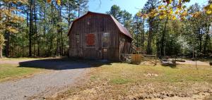 Rustic barn style house with garage downstairs. Metal roof, cedar interior walls. Staircase to loft. There are closets in the loft bedroom and in downstairs sleeping area. The tankless water in utility room downstairs. Deck on back overlooking the pond. Fenced yard with graveled sitting area with firepit also has fencing around deck railing for safety. Granite kitchen, commercial gas cookstove and vent. Refrigerator and propane tanks convey There is a wood stove downstairs, not hooked up, but will convey with the house. Very private setting to enjoy nature and wildlife. Square footage is what is shown in tax record. There is a loft and full first floor is utility, garage, storage.