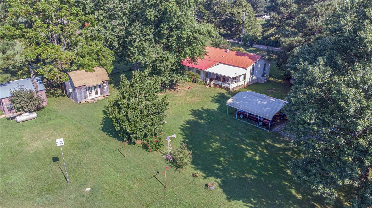 SOLD AS-IS. Cute home on 5 acres with a metal roof! Great opportunity for the hobby farmer - chickens, cows, etc. Open living area with wood laminate floors leading into the kitchen. Kitchen has stainless steel appliances, plenty of cabinet space and dining area just off the kitchen. Great bonus room/office space just past the kitchen. Sit out & enjoy the peaceful surroundings out on the covered back porch. Already setup to easily add a wood-burning stove. New septic tank & lateral lines. Awesome detached 10.5x16 hobby house with insulation, A/C & electrical. 16x12 workshop insulated with A/C & electrical. Large barn great for storage. Come see this great property!