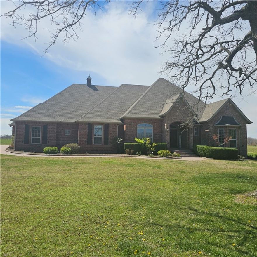 Estate home sitting on 12.18 acres. All open and level except perimeter with wooded acres.  Great for feel of seclusion, yet close to town.  Less than 1/2 mile of gravel road.  Shared pond. 4 or could be 5 BR home.  All on one level except Theatre/Media/Game room upstairs w/ large walk-in closet for storage and/or media equipment.  110” movie screen w/projector, rope lighting and surround sound.  Massive custom trim package w/crown molding & wood window toppers.  One owner custom built home in 2007.  All appliances stay, including Gas propane countertop stove, microwave/convection/conventional oven, ice machine, built in warming drawer/slower cooker, trash compactor, vented hood, dishwasher, smart refrigerator, washer/dryer.  Gas log fireplace & mini-split in enclosed patio with shake shingles on walls & real wood ceiling for lodge like setting.  Upgraded electrical and plumbing fixtures, heated whirlpool tub,2 lg walk-in closets, separate stool area, and sep shower. Oversized 3 car garage & much more. Agent Owned